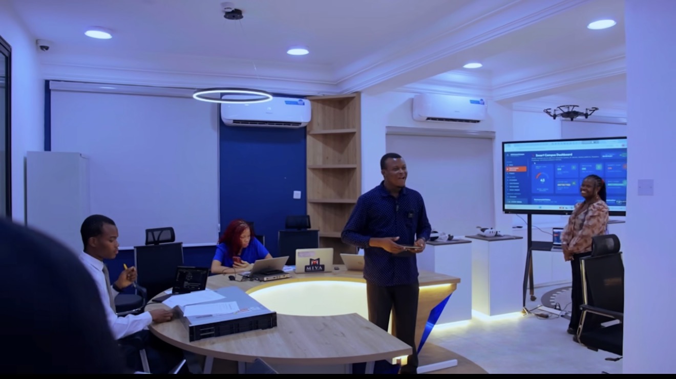 Presentation in the Miva Open University Robotics & Innovation Laboratory, with a dashboard on a large screen and people seated at the lab table